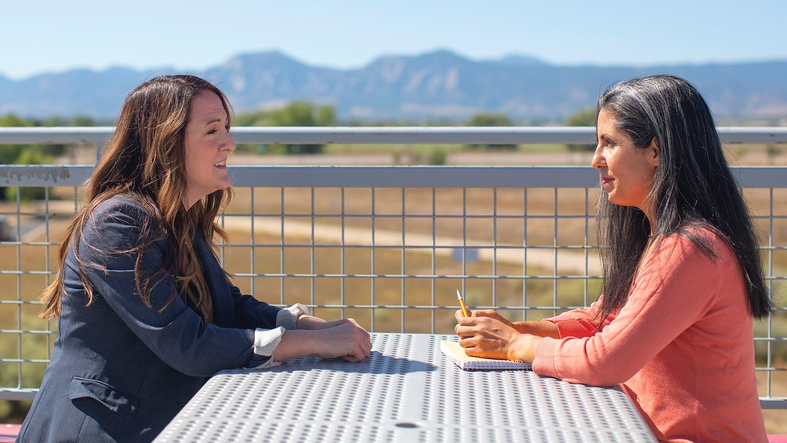 Two women meeting on a patio outside in the mountains